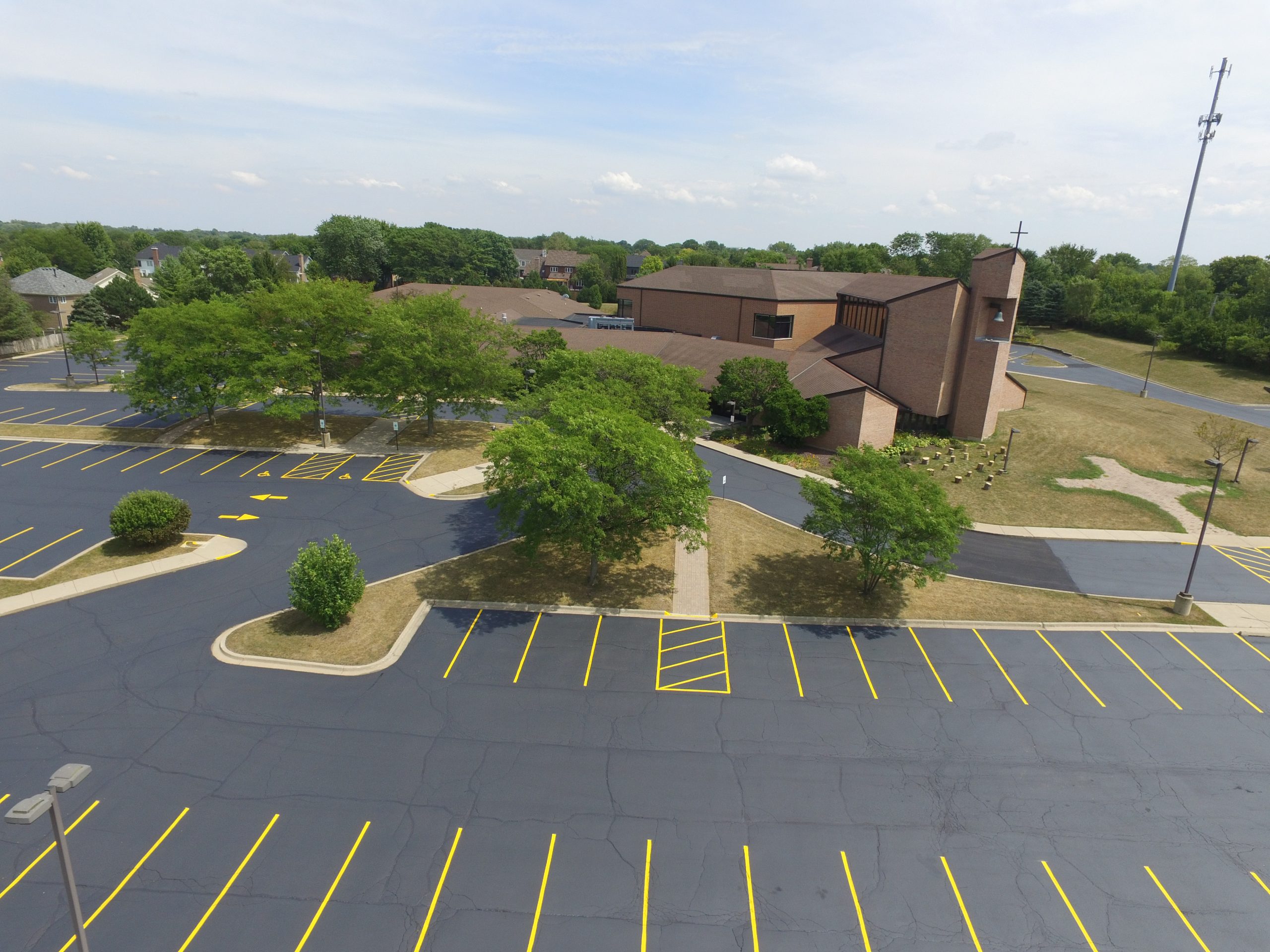 417 Striping & Sealing parking lot sealcoating project at Immanuel Lutheran Church and School in Batavia with freshly sealed asphalt surface
