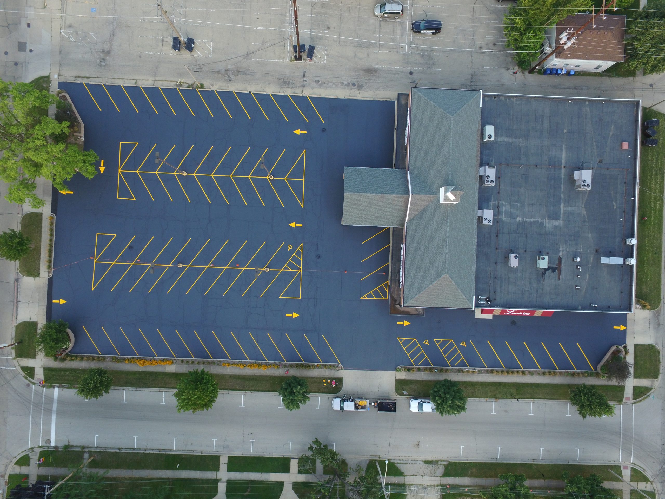 417 Striping & Sealing parking lot sealcoating project at The Lincoln Inn at Faranda’s in DeKalb with freshly sealed asphalt surface